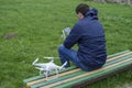 A man with a remote control quadroopter in his hands is sitting on a bench. White quadroopter prepare for flight. Royalty Free Stock Photo