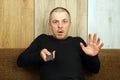 The man with the remote control for the TV in shock stares at the screen Royalty Free Stock Photo