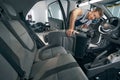 Man removes automobile seat for cleaning interior in car service