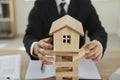 Man removes blocks from under small wooden house, demonstrating importance of home insurance.