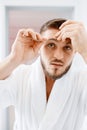 Man removes eyebrow hair, morning hygiene