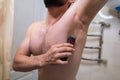 A man removes his armpit hair with an electric razor. A man with an athletic figure in the bathroom