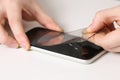 man removes old cracked protective glass from phone. Broken glass