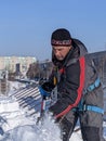 A man removes snow from the roof against the blue sky in winter. Daily work of climbers in Russia in winter.