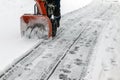 A man removes snow from sidewalks with a snow blower in winter at an electrical substation Royalty Free Stock Photo