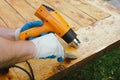 Man removing old varnish from wood using scraper and heat gun.