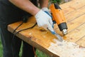 Man removing old varnish from wood using scraper and heat gun. Royalty Free Stock Photo