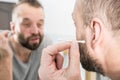 Man removing wax from ear using Q-tip Royalty Free Stock Photo