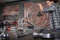 Man repair the bicycle in garage workshop on the workbench with tools, with the brush on the wheel, diy concept, red bricks Royalty Free Stock Photo