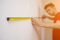 Man repair measures the white wall of the with a tape measure and before wallpapering. renovation apartment Royalty Free Stock Photo