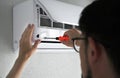 A man repairing an air conditioner at home. technician repairman. the man unscrews the screw in the air conditioner for cleaning. Royalty Free Stock Photo