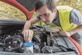 Man is repairing car and checking engine coolant