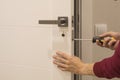 Man repairing the doorknob. closeup of worker`s hands installing new door locker Royalty Free Stock Photo