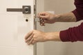 man repairing the doorknob. closeup of worker& x27;s hands installing new door locker Royalty Free Stock Photo