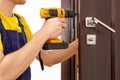 a man repairing a doorknob. Handyman repair the door lock in the room.