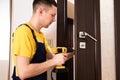 a man repairing a doorknob. Handyman repair the door lock in the room.