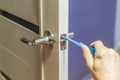 Man repairing the doorknob with screwdriver. worker`s hand installing new door locker Royalty Free Stock Photo