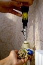 A man is repairing a heating radiator. A plumber works with a yellow screwdriver in a private apartment