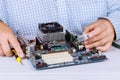 Man repairman is trying to fix using the tools on the computer that is on a workplace in the office. Royalty Free Stock Photo