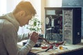 Man repairman is trying to fix using the tools on the computer that is on a workplace in the office Royalty Free Stock Photo