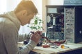 Man repairman is trying to fix using the tools on the computer that is on a workplace in the office Royalty Free Stock Photo