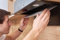 Man repairs hood in kitchen. Replacement filter in cooker hood