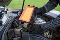 Man replaces a dirty air filter for a new one in a car.