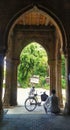 Man resting in cool shadow under the arches of a historic building in India