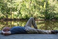 Man resting lying down alone on rustic dock by tranquil woodland pond