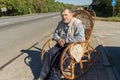 Man resting while sitting in a wicker rocking-chair at roadside at sunny autumnal day