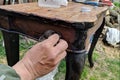 A man restores old furniture in the fresh air. Removes old paint from a vintage table.