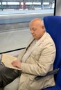 The man of a retirement age reads the book in the electric train car Royalty Free Stock Photo