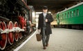Man in retro suit with suitcase walking on the train platform