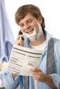 Man reviewing document while shaving