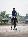 Man rider and black stallion eventing horse trotting leg-yield during equestrian dressage competition Royalty Free Stock Photo