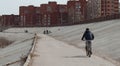 A man rides a Bicycle along a concrete road near the pond,