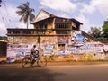A man rides a bicycle past the grungy decaying walls of an old vintage house in the