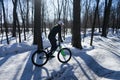 A man rides a bicycle on a pump-track in the winter in a helmet.