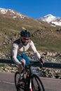 A man rides a bicycle on a road with a mountain and a river in the background