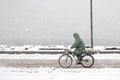 Man rides a bicycle in a snowfall in a road