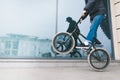 Man rides a bike on the back wheel of a BMX against a glass shop window. A teen makes tricks on a BMX bike Royalty Free Stock Photo