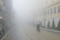 A man rides his motorcycle through dense fog in the city Royalty Free Stock Photo