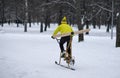 A man rides a homemade bicycle with a propeller in the snow.Snowbike in the park. Bike with skis.