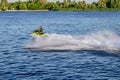 A man rides a PWC on the Dnieper River in Kherson, Ukraine - back view. White foam, splashes and trail created by a jet ski on the