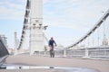 Man riding on bicycle across the bridge in the city. Royalty Free Stock Photo