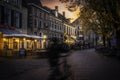 the man is riding a bicycle down the street at dusk