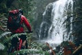 a man is riding a bike through the forest past a waterfall