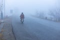 Man riding on a bike going for work in thick fog in swat valley, Pakistan Royalty Free Stock Photo