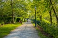 A man is riding a bike under green trees and a girl is sitting on a bench. Pittsburgh, Pennsylvania, US