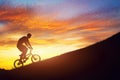 Man riding a bmx bike uphill against sunset sky. Strength, challenge.